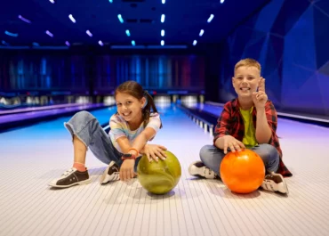 Deux enfants assis devant une piste de bowling