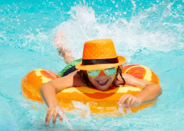 Petite fille portant chapeau et lunette de soleil s'amuse dans l'eau avec sa bouée
