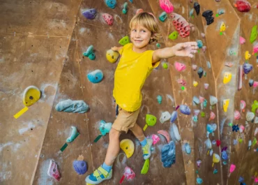 Un enfant fait de l'escalade sur un mur de grimpe a paris