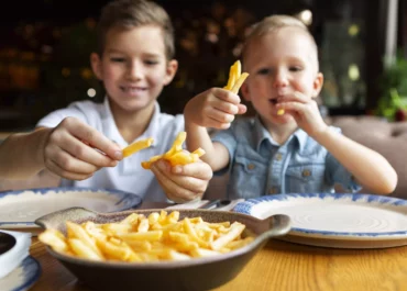 Deux garçons mangeant des frites dans un restaurant en ile de france